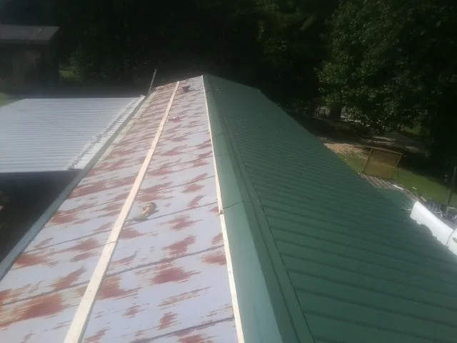 Old rusted panels beside newly installed green metal roofing — Wind Damage Roof Repair by Roofing Brothers in Sharon Hill