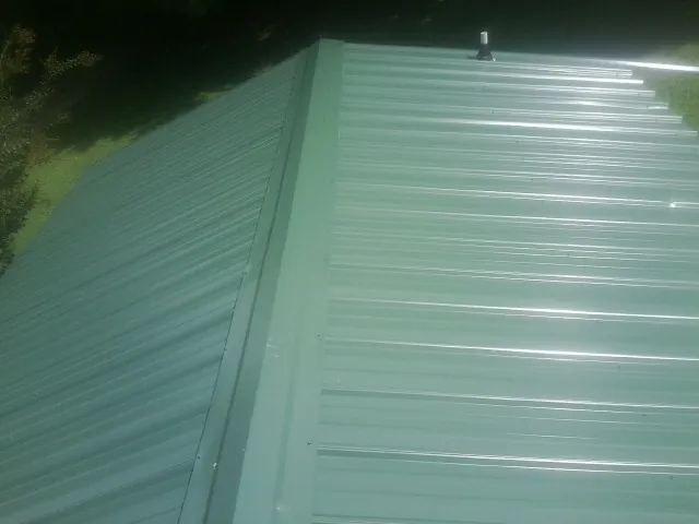 New green metal panels meeting at the ridge of a roof — Flat Roof Repair work by our crew in Sharon Hill