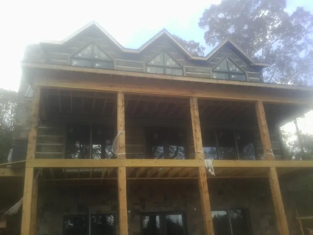 Dormers and porch framing on a large log home under construction — Roof Coating work by our crew in Sharon Hill