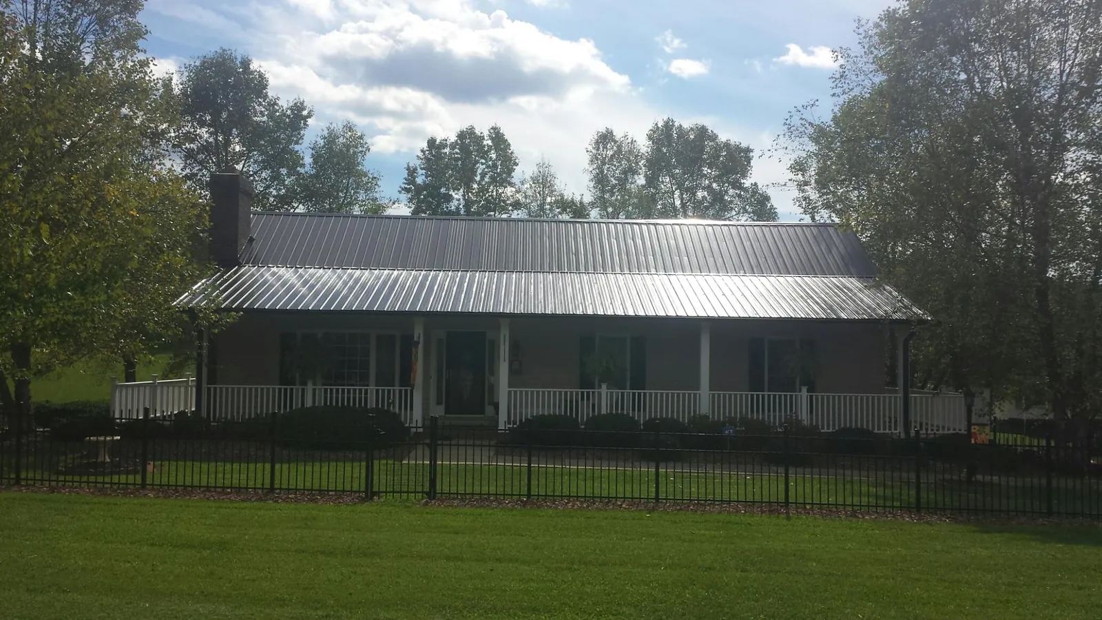 Gray metal roof on a brick ranch with a full width front porch — Gutter Guard Installation work by our crew in Sharon Hill