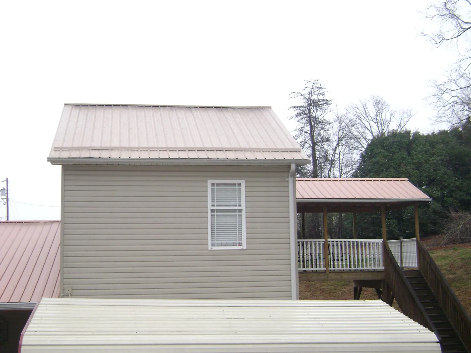 Tan metal roofs on a two story addition and attached porch, from a Roof Replacement job in Sharon Hill